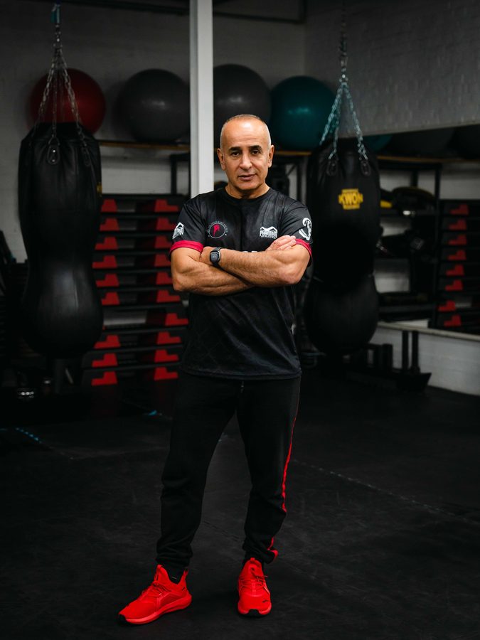 Dai Sifu Reza Shouraki steht mit verschränkten Armen vor den Sandsäcken seiner Trainingshalle.