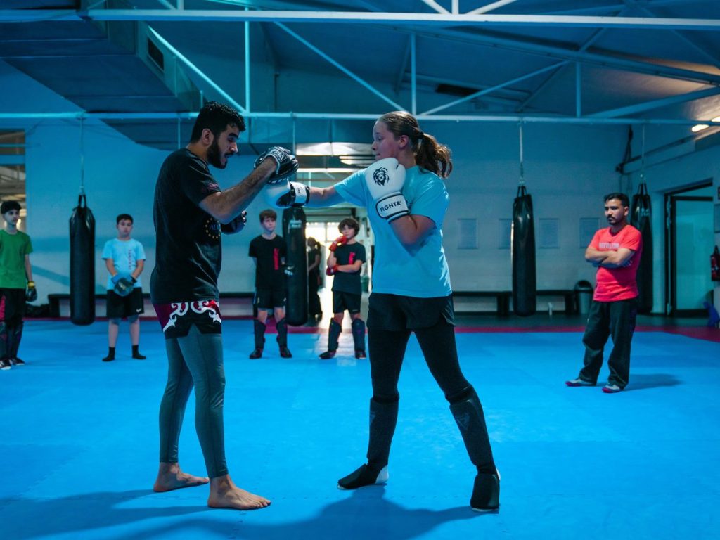 Gürtel und Graduierungen im Kampfsport: Was sie bedeuten 1 Trainer und Trainierende konzentriert im Pratzentraining, beide Gesichter einander zugewandt.