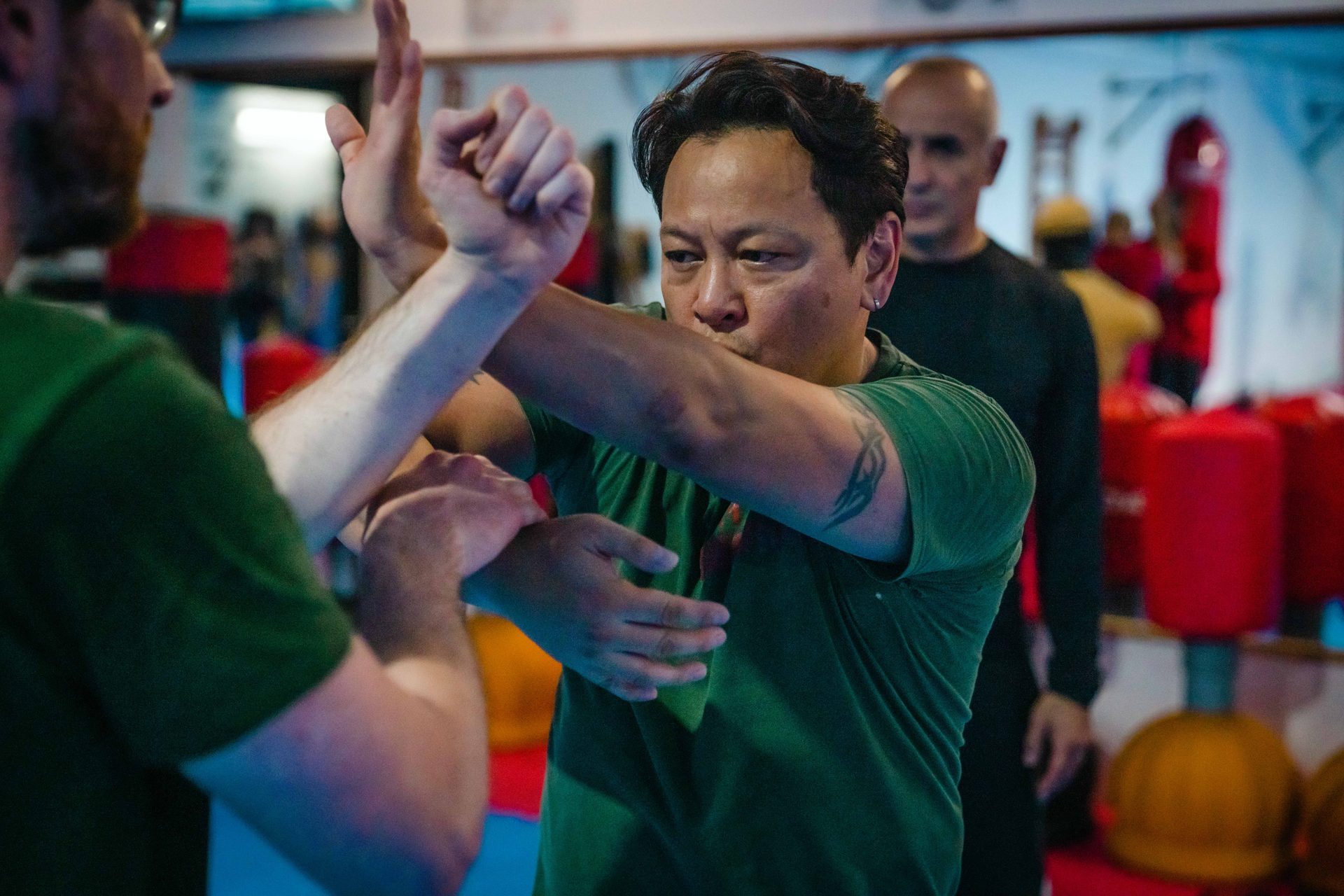 Wing-Chun-Partnerübung mit Abwehrbewegung zwischen zwei Trainierenden in der Halle.
