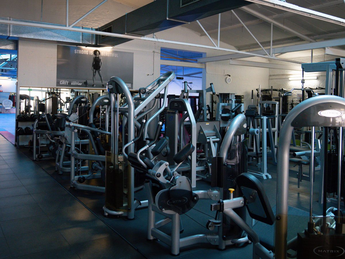 Blick über den Gerätepark des Fitnessstudios mit Kraftmaschinen in mehreren Reihen.