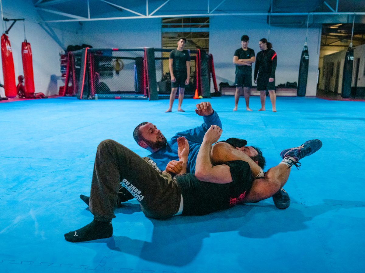 BJJ-Technik im Bodenkampf-Training in Aachen: Ein Trainierender kontrolliert den Arm seines Partners in der Bodenlage auf der blauen Matte.