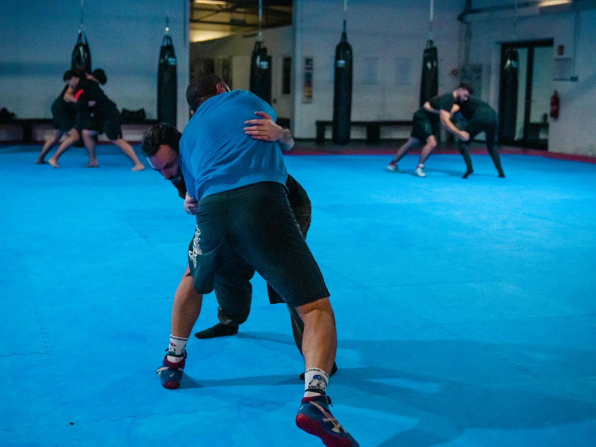 Zwei Trainierende ringen im Clinch um die bessere Position, im Hintergrund weitere Paare beim Grappling-Training.
