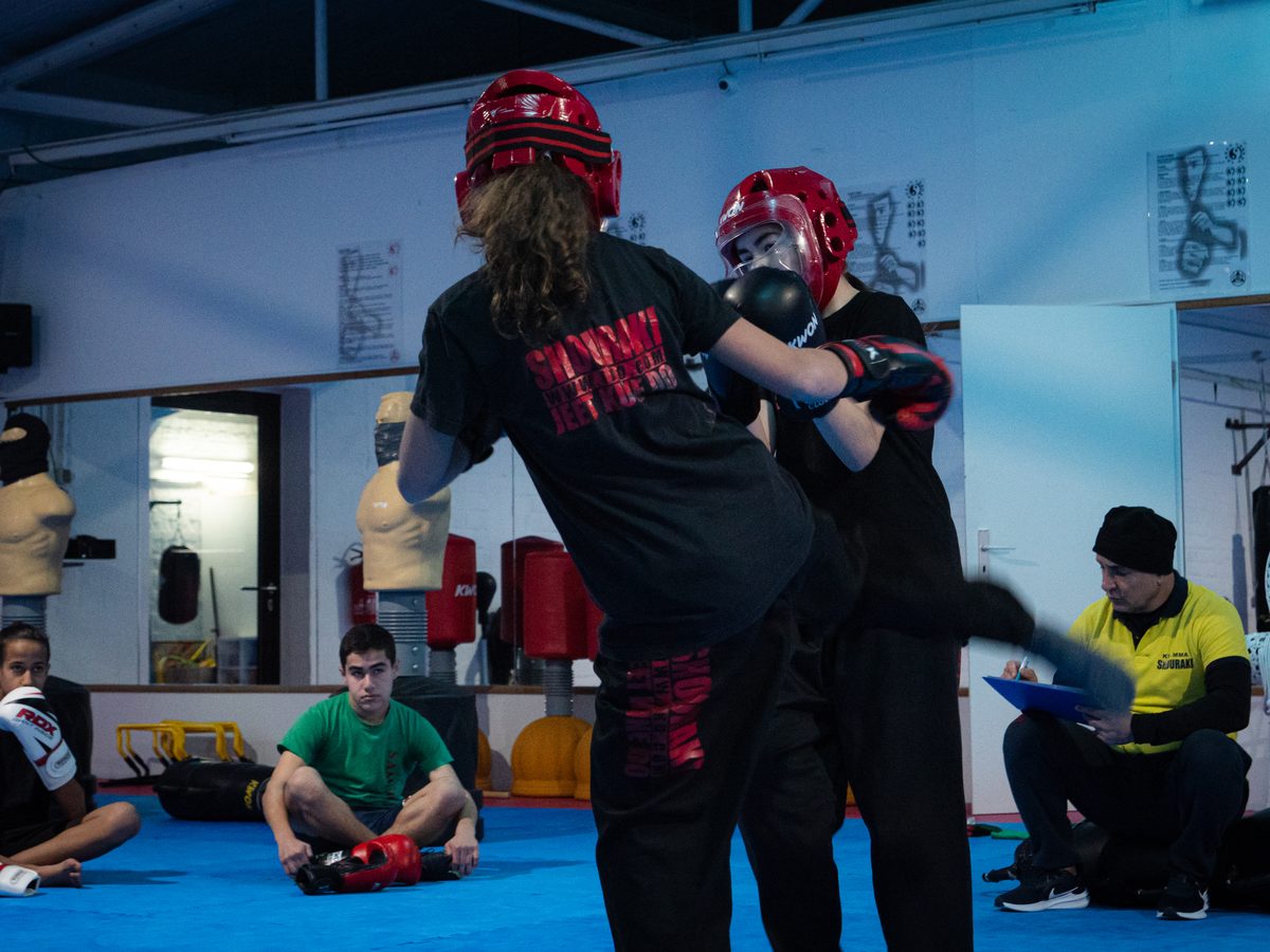 Zwei Jugendliche mit Kopfschutz im Sparring-Clinch während der Gürtelprüfung.