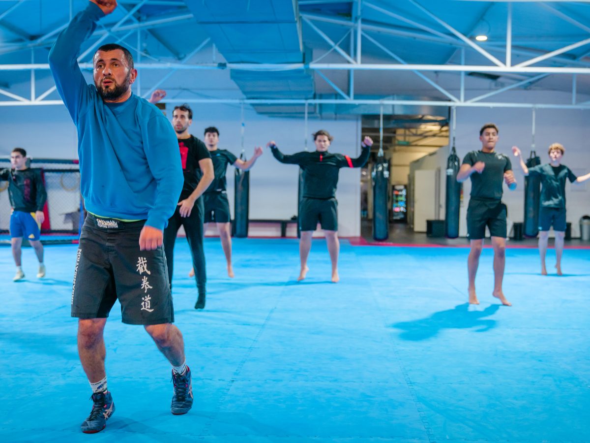 Kickboxen in Aachen 2 Trainer leitet die Gruppe beim Aufwärmen mit einer Sprungübung in der Trainingshalle an.