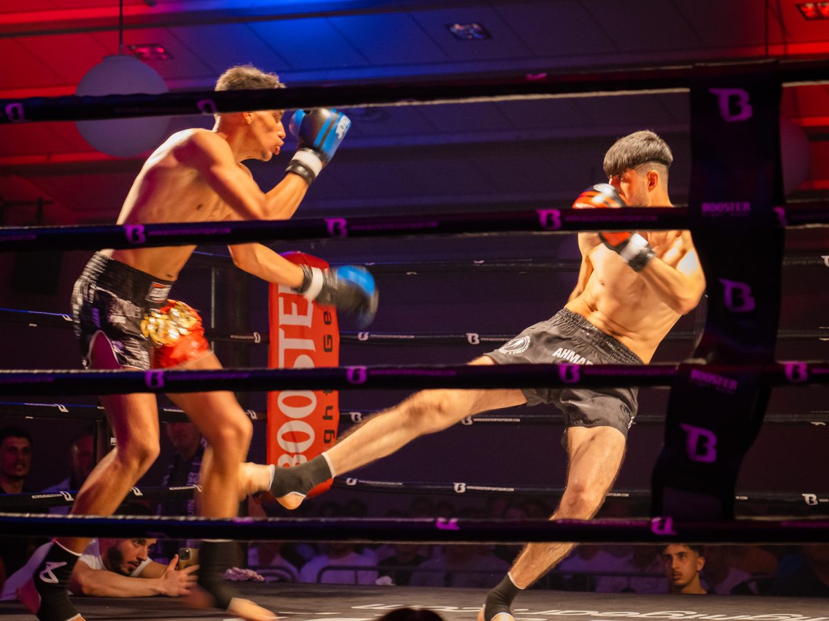Kickboxen in Aachen 8 Hoher Kick im Ring bei rot-blauem Bühnenlicht während eines Wettkampfabends.