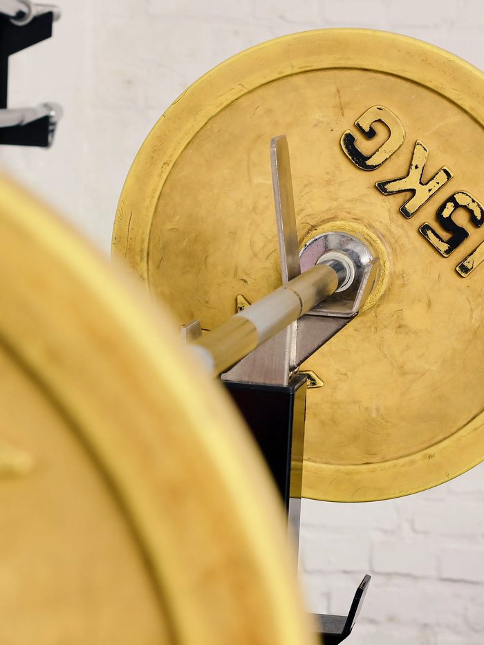 Nahaufnahme zweier goldener Langhantel-Gewichtsscheiben im Fitnessbereich.