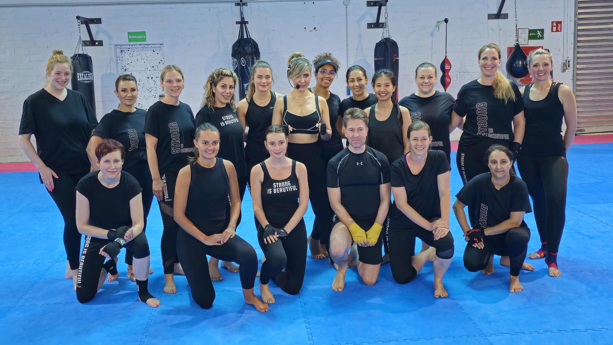 Große Frauengruppe nach dem LES MILLS BODYCOMBAT-Kurs in der Trainingshalle.