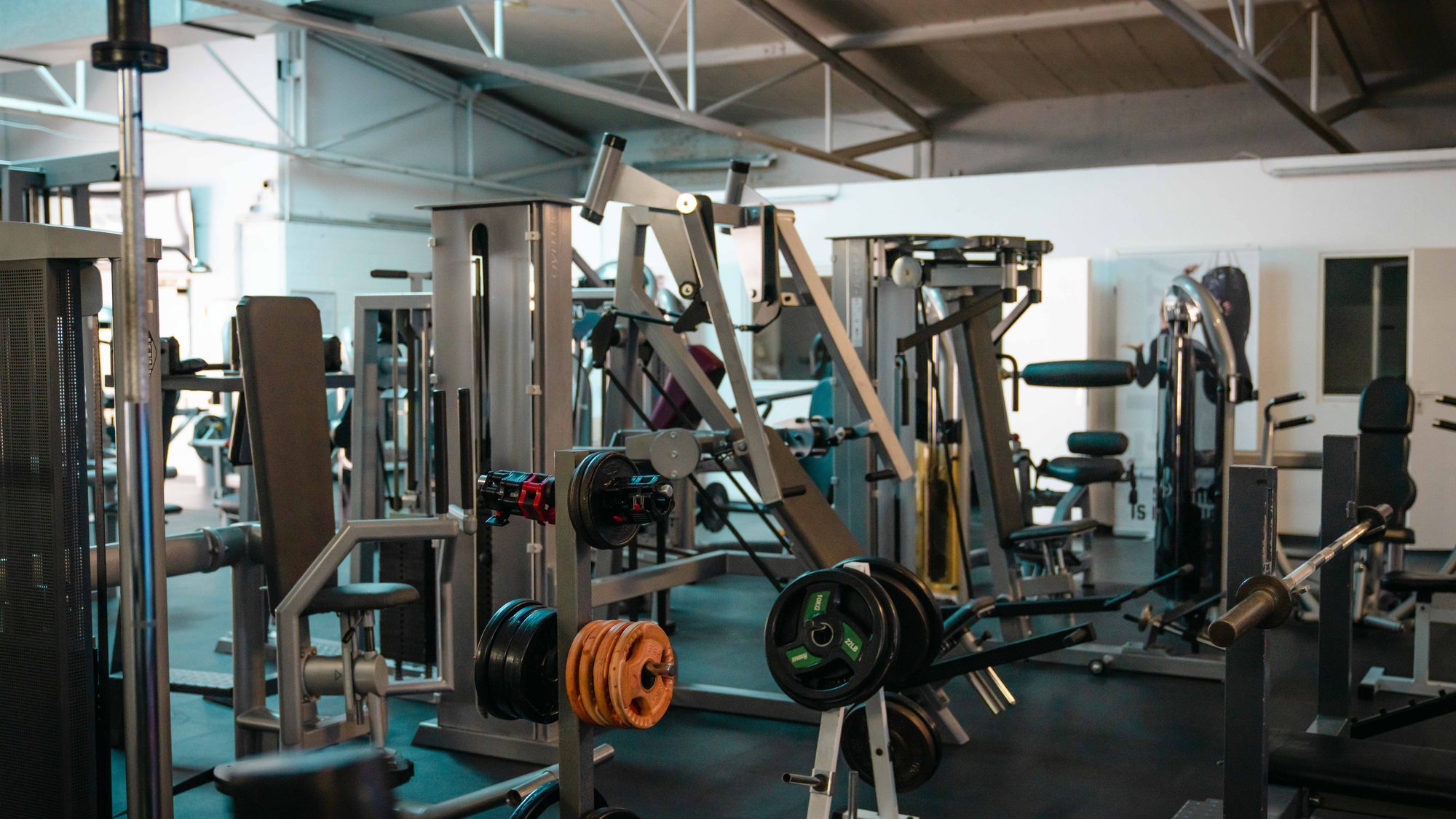 Fitness Aachen: Blick in den Gerätebereich des Fitnessstudios mit Kraftgeräten und Hantelscheiben.