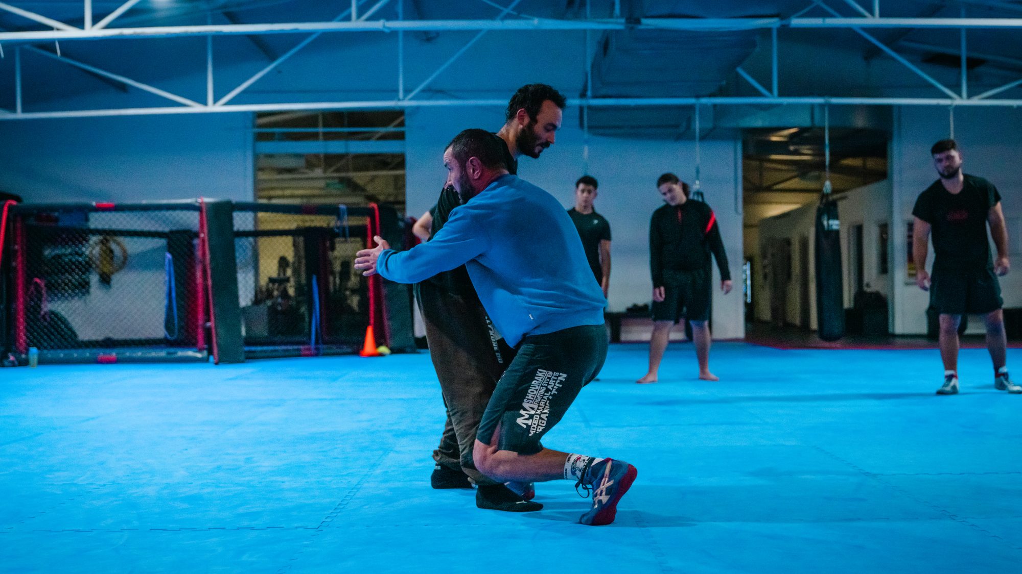 Takedown im Grappling-Training auf der blauen Matte der Trainingshalle.