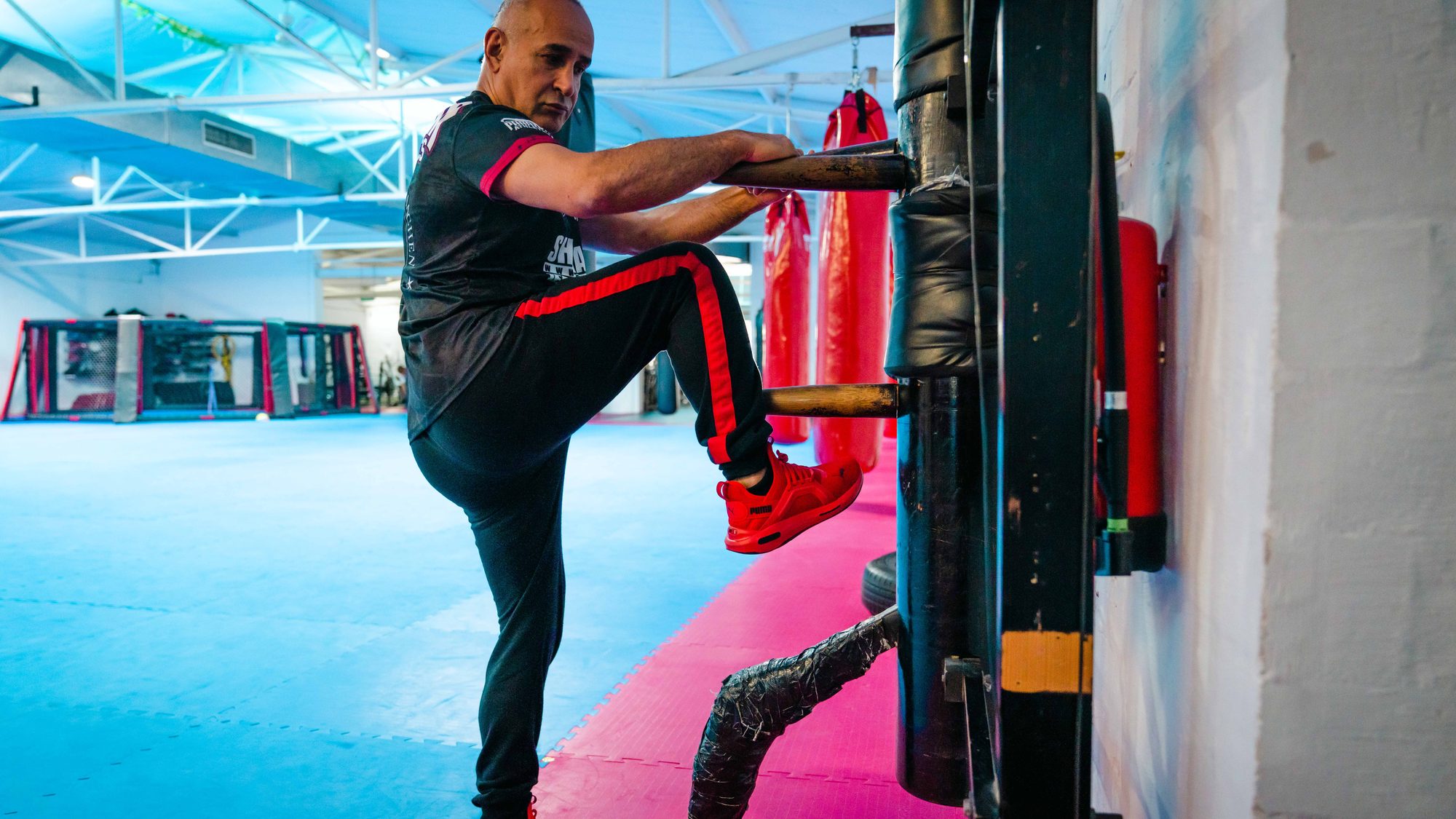 Der Sifu führt einen Seitkick gegen die Wing-Chun-Holzpuppe aus.