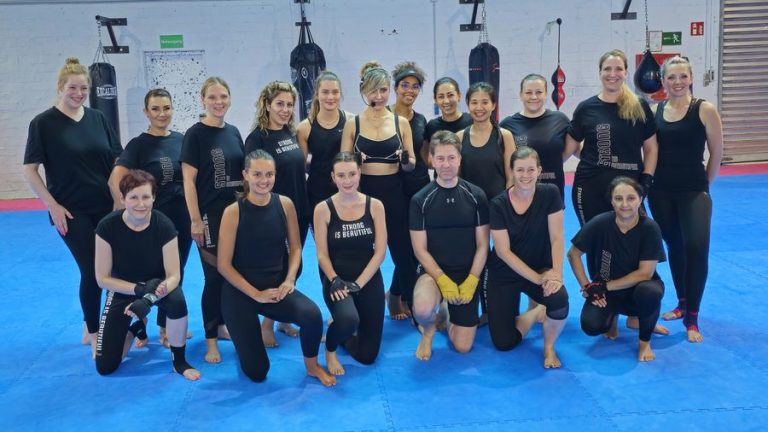 Rund zwanzig Teilnehmerinnen des BODYCOMBAT-Kurses stellen sich nach der Stunde zum Gruppenfoto auf.