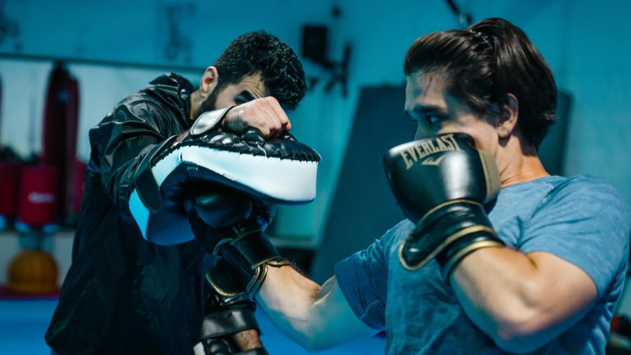 Nahaufnahme im Boxtraining: Ein Boxhandschuh trifft die vorgehaltene Pratze des Partners.