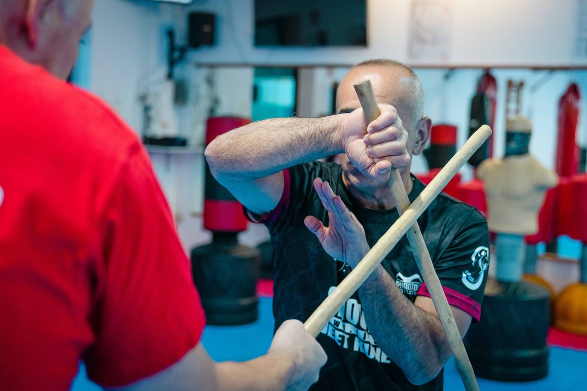 Zwei Trainierende üben im Kali-Escrima-Training eine Abwehr mit Rattanstöcken.