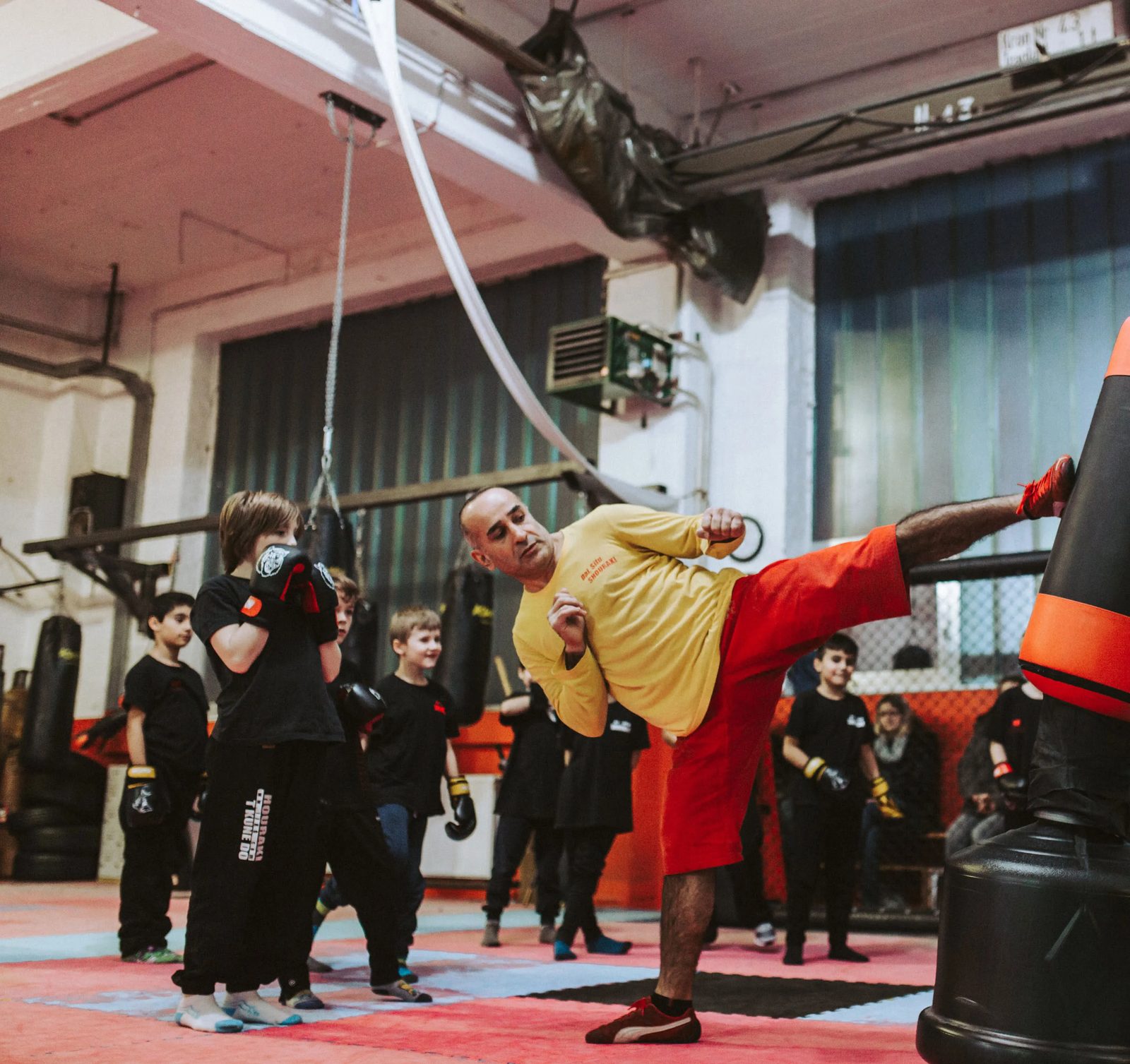 Probetraining 2 Der Sifu zeigt der zuschauenden Trainingsgruppe einen hohen Kick am Standsack.